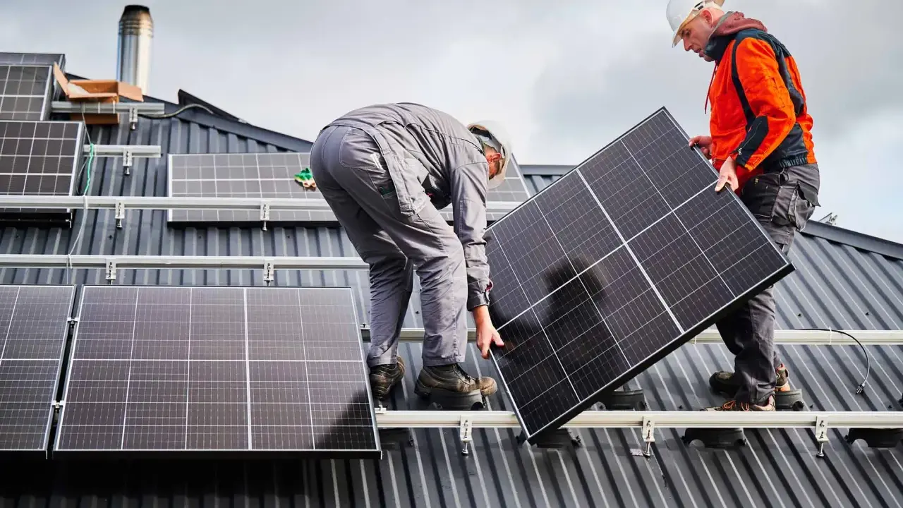 Deux ouvriers installent un panneau solaire sur un toit. La dimension du panneau solaire est adaptée pour maximiser la capture d'énergie.