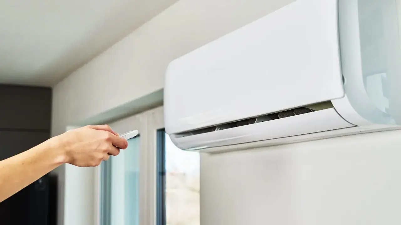 Main tenant utilise la télécommande pour régler le voyant clim.