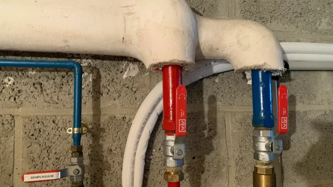 Système de chauffage avec tuyaux isolés. Une vanne marquée "REMPLISSAGE" est visible.