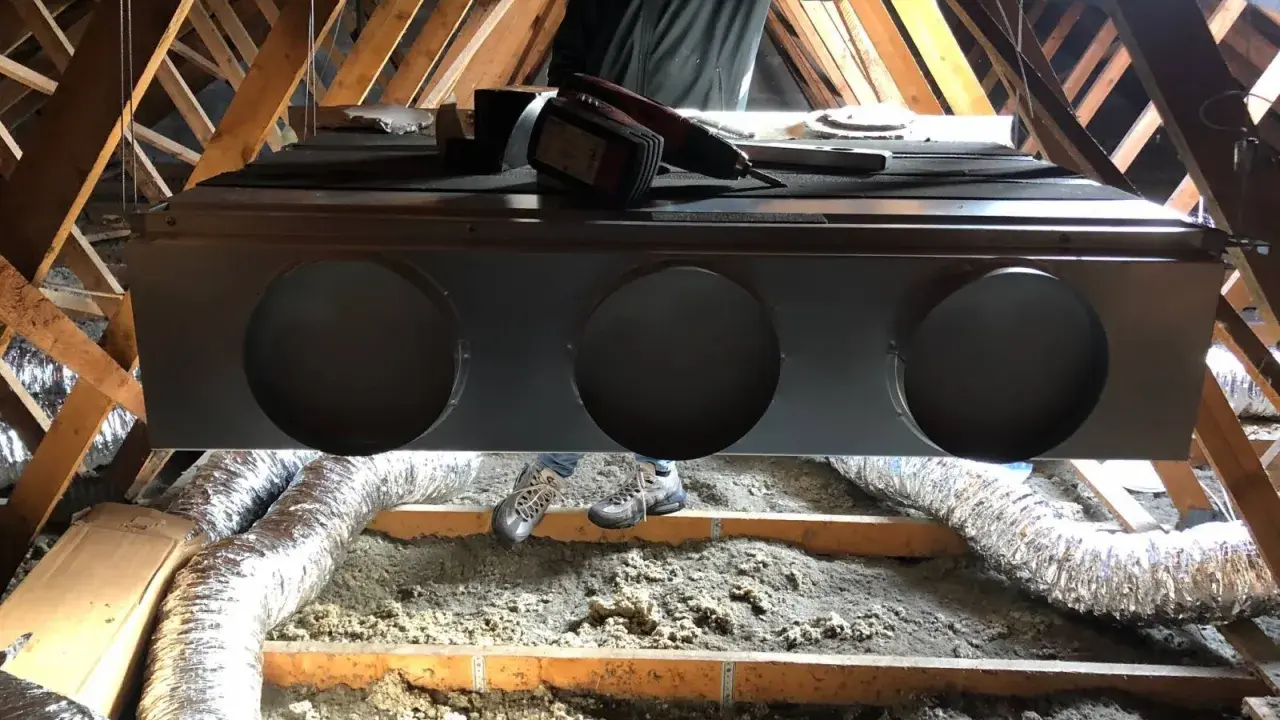 Installation d'un système de climatisation gainable dans un grenier. Un technicien est visible, prêt pour l'entretien.