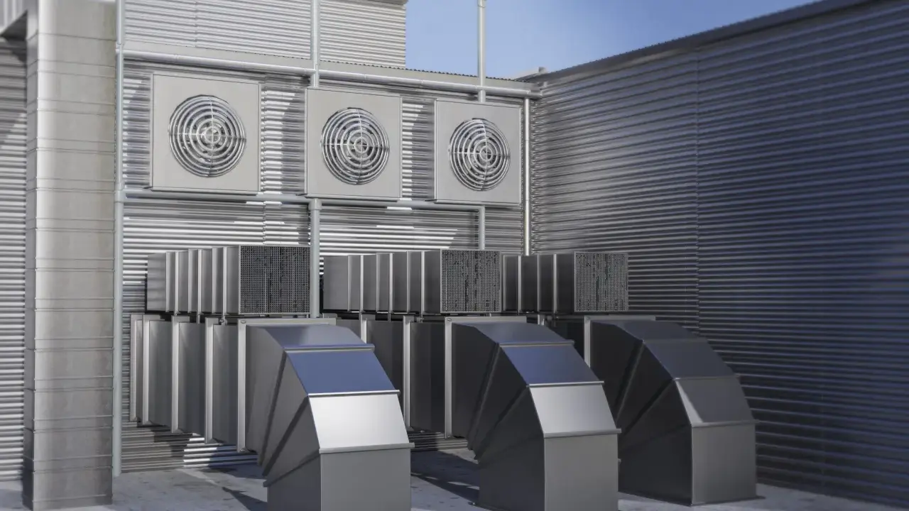 Système de ventilation extérieure avec plusieurs ventilateurs et conduits métalliques. Ce système pourrait être une VMC hygroréglable ou autoréglable pour un bâtiment.
