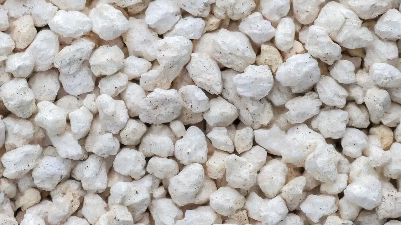Gros plan sur une texture de perlite exfoliée, de petites roches blanches et poreuses, parfaites pour l'aération du sol.