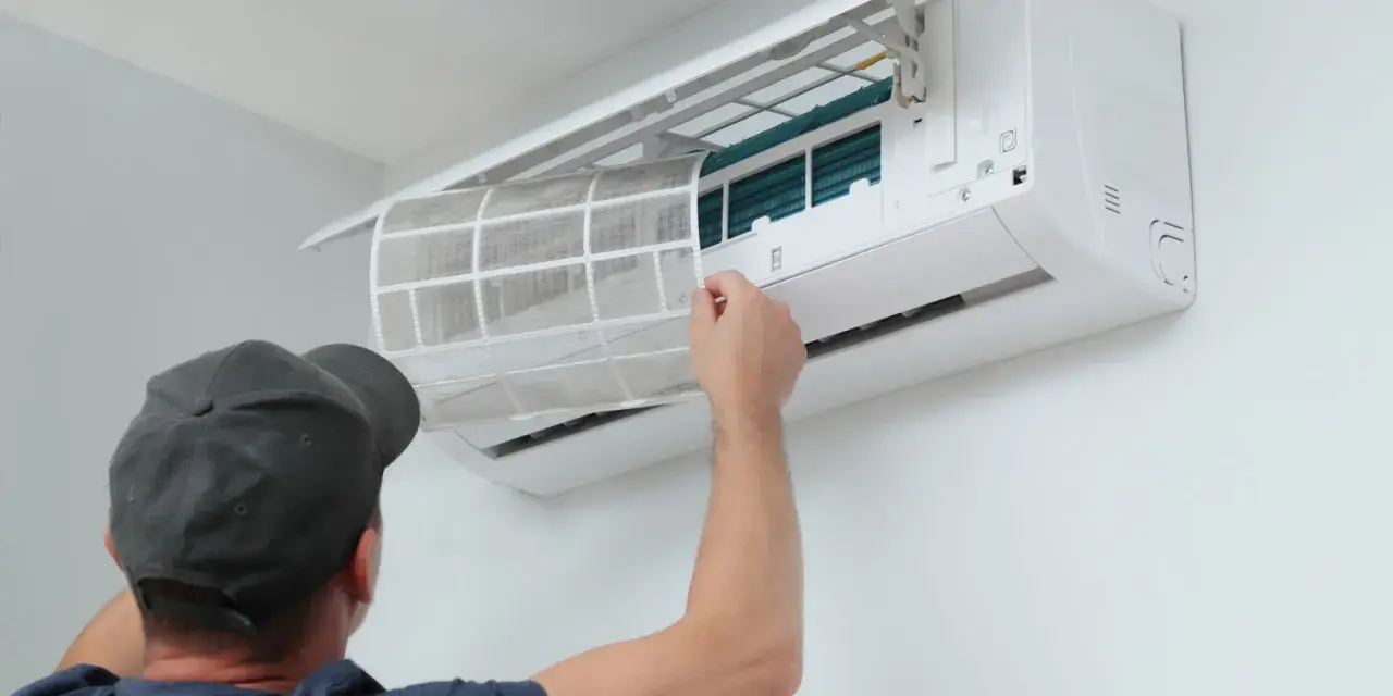 Un technicien nettoie le filtre d'une climatisation réversible. Un entretien régulier assure un air sain et optimise le tarif entretien clim réversible.