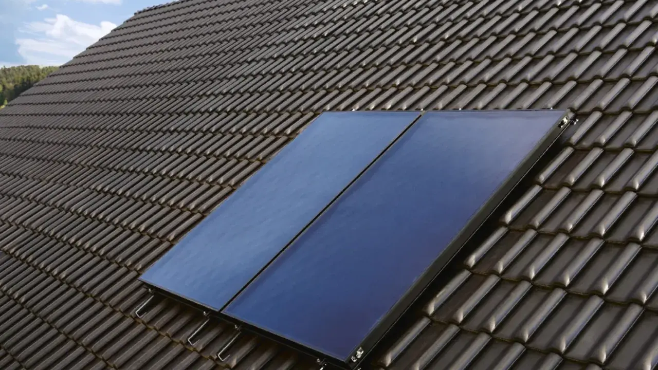 Deux panneaux solaires bleus sont installés sur un toit en tuiles sombres, captant l'énergie pour le chauffage solaire.