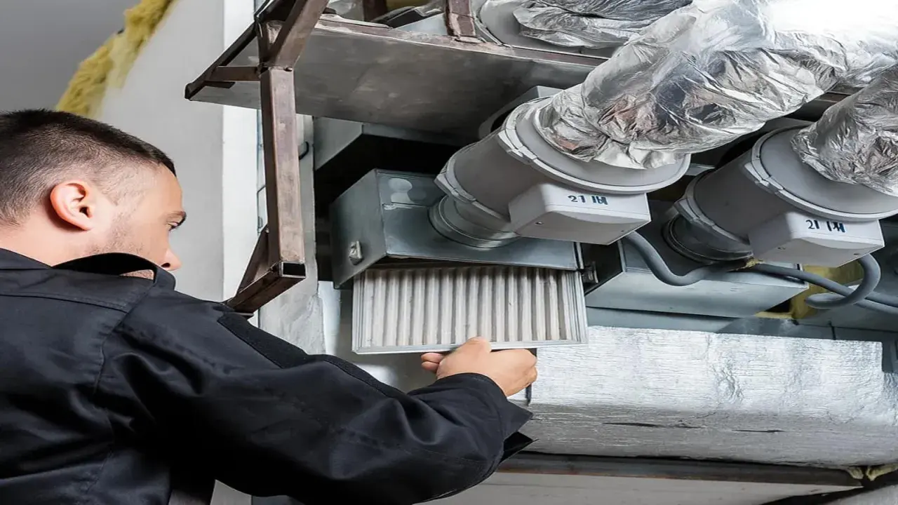 Un technicien retire un filtre encrassé d'un système de ventilation, signe que la vmc ne fonctionne plus correctement.