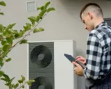 Un technicien vérifie une pompe à chaleur, soulignant l'avantage d'une solution de chauffage écologique et économique.
