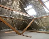 Isolation des combles 100m2 : vue d'un grenier en cours d'isolation avec matériaux réfléchissants et charpente bois.