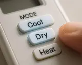 Doigt appuyant sur le bouton "Cool" d'une télécommande de climatiseur. Le mode cool est idéal pour les journées chaudes.