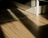 Rayons de soleil traversant un tapis sur un plancher de bois. L'isolation du plancher bois est discrète sous le tapis.