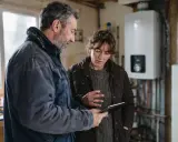Un couple discute sur une tablette, visiblement déçu par un refus de banque pour un éco-prêt à taux zéro.