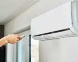 Main tenant utilise la télécommande pour régler le voyant clim.