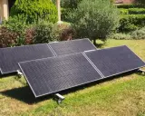 Panneaux solaires sur pelouse, promesse de rentabilité panneau solaire autoconsommation. Jardin verdoyant, maison en arrière-plan.