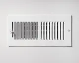 Grille de ventilation blanche, partie intégrante d'une installation pompe à chaleur air air gainable, pour une diffusion discrète de l'air.