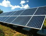 Panneaux solaires installés sur un terrain herbeux, sous un ciel bleu avec des nuages. Idéal pour apprendre comment installer des panneaux solaires soi même.