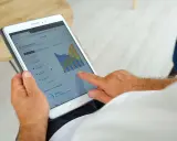 Homme consultant sa tablette : suivi de production solaire, consommation, autoconsommation et injection gratuite ENEDIS.