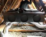 Installation d'un système de climatisation gainable dans un grenier. Un technicien est visible, prêt pour l'entretien.