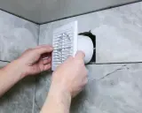 Installation d'une grille de ventilation VMC pour lutter contre la condensation dans une salle de bain carrelée.