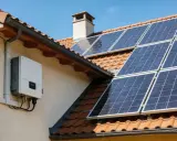 Panneau solaire sur un toit avec un onduleur blanc. Pour savoir si un onduleur ne fonctionne plus, vérifiez son écran ou les voyants lumineux.