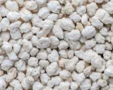 Gros plan sur une texture de perlite exfoliée, de petites roches blanches et poreuses, parfaites pour l'aération du sol.