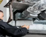 Un technicien retire un filtre encrassé d'un système de ventilation, signe que la vmc ne fonctionne plus correctement.