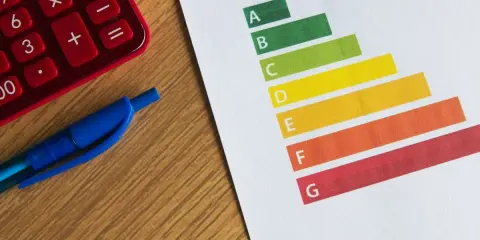 Calculatrice rouge, stylo bleu et graphique DPE. Le gel des loyers pourrait impacter les logements classés E.