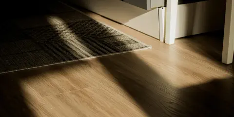 Rayons de soleil traversant un tapis sur un plancher de bois. L'isolation du plancher bois est discrète sous le tapis.
