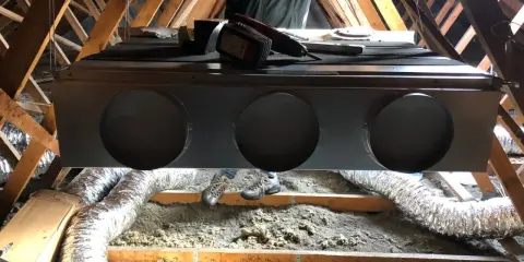 Installation d'un système de climatisation gainable dans un grenier. Un technicien est visible, prêt pour l'entretien.