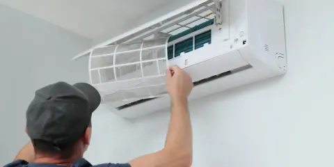 Un technicien nettoie le filtre d'une climatisation réversible. Un entretien régulier assure un air sain et optimise le tarif entretien clim réversible.