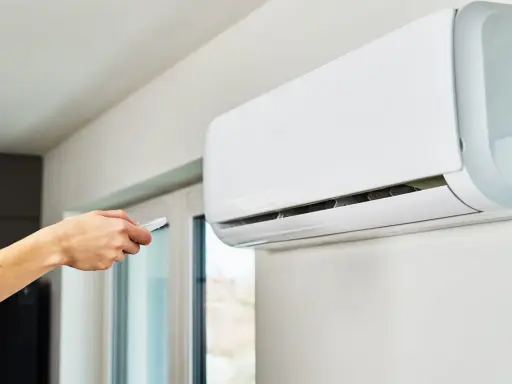 Main tenant utilise la télécommande pour régler le voyant clim.