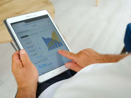 Homme consultant sa tablette : suivi de production solaire, consommation, autoconsommation et injection gratuite ENEDIS.
