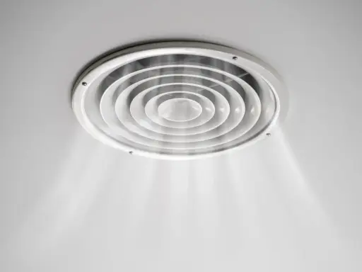 Grille de ventilation ronde au plafond, diffusant une légère brume. On dirait que la VMC pas assez puissante peine à renouveler l'air.