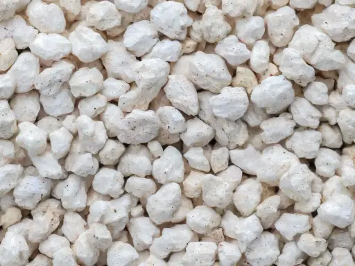 Gros plan sur une texture de perlite exfoliée, de petites roches blanches et poreuses, parfaites pour l'aération du sol.