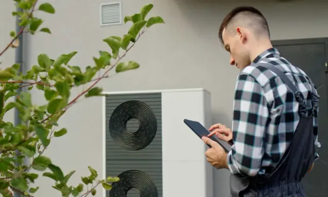Un technicien vérifie une pompe à chaleur, soulignant l'avantage d'une solution de chauffage écologique et économique.