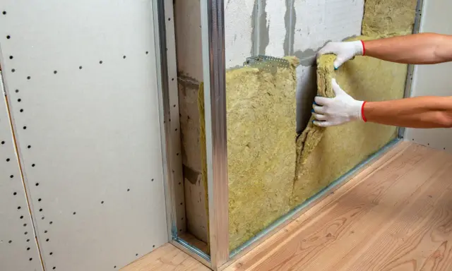 Pose d'isolant minéral pour comment insonoriser une chambre à coucher. Pose de laine de roche dans une structure métallique.
