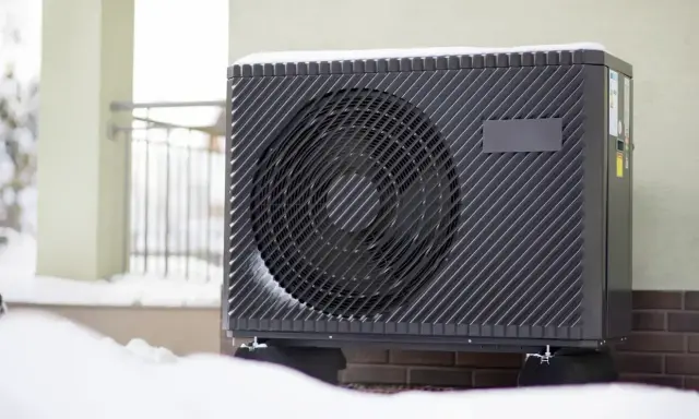 Unité extérieure de climatisation recouverte de neige, signe qu'elle givre.