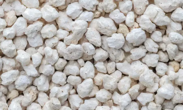 Gros plan sur une texture de perlite exfoliée, de petites roches blanches et poreuses, parfaites pour l'aération du sol.