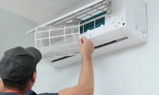 Un technicien nettoie le filtre d'une climatisation réversible. Un entretien régulier assure un air sain et optimise le tarif entretien clim réversible.