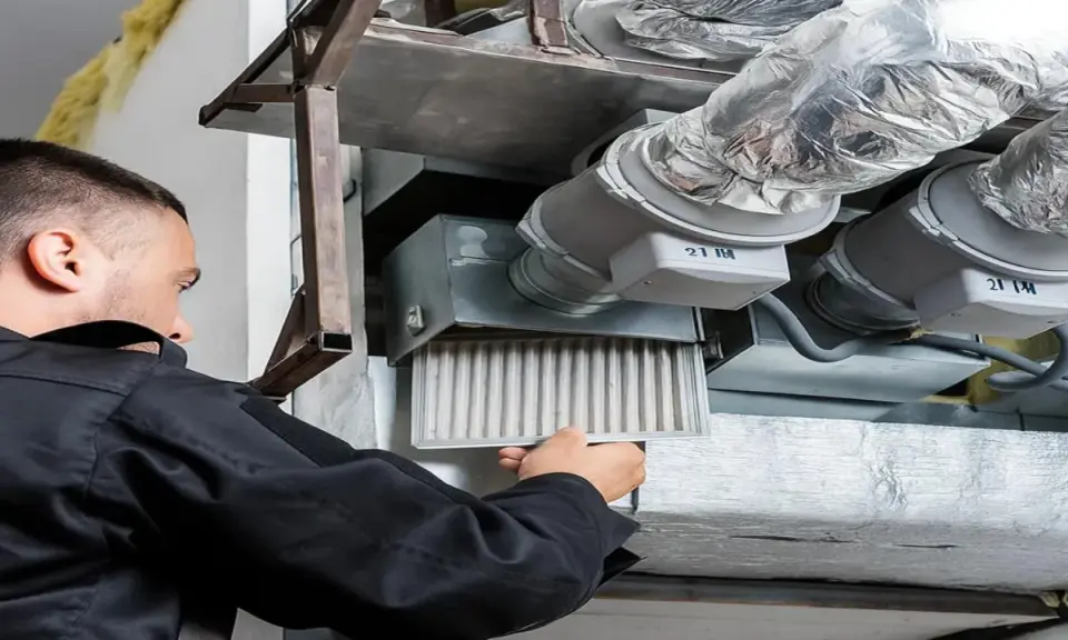 Un technicien retire un filtre encrassé d'un système de ventilation, signe que la vmc ne fonctionne plus correctement.