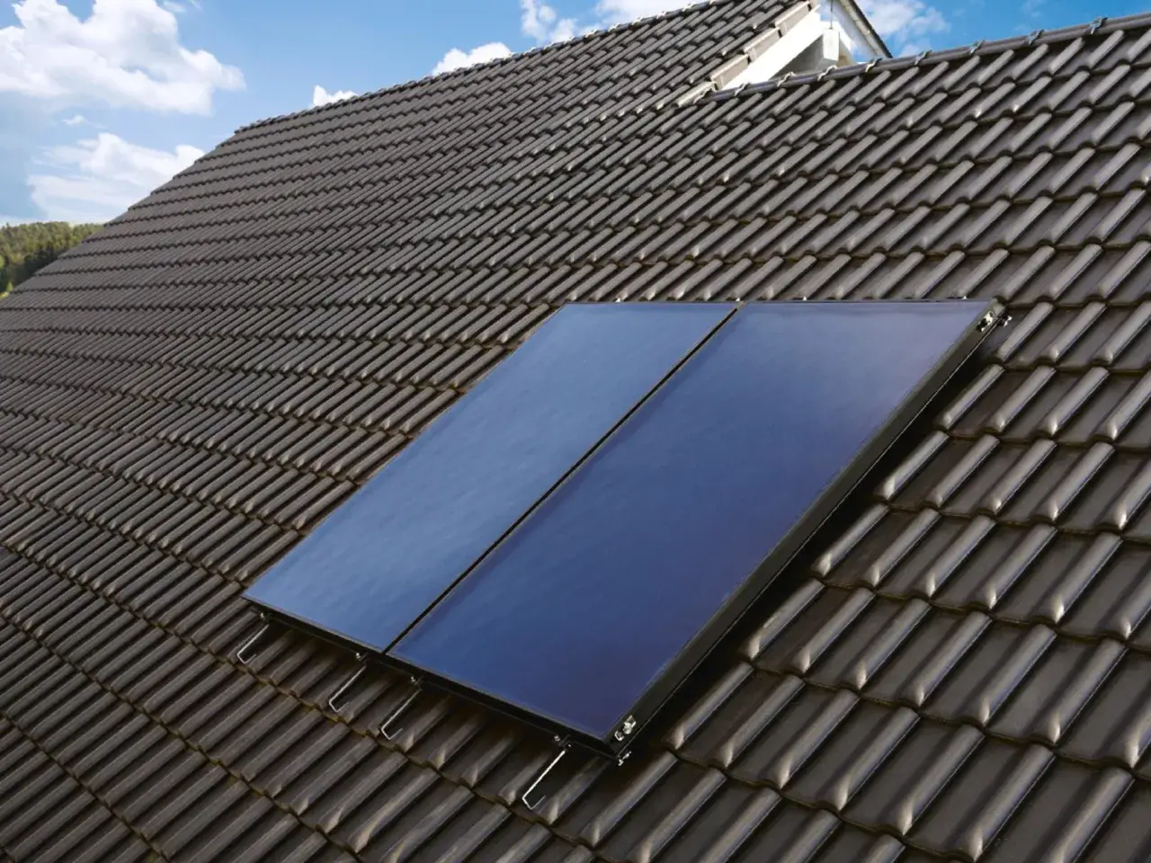 Deux panneaux solaires bleus sont installés sur un toit en tuiles sombres, captant l'énergie pour le chauffage solaire.