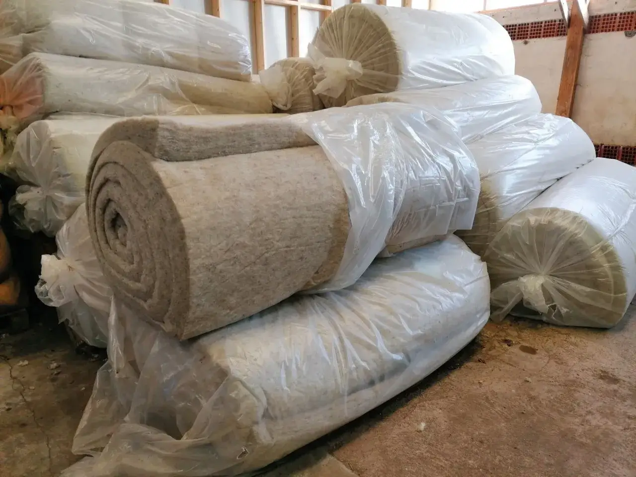 Rouleaux de laine de mouton pour isolation, empil&eacute;s et emball&eacute;s dans du plastique transparent.
