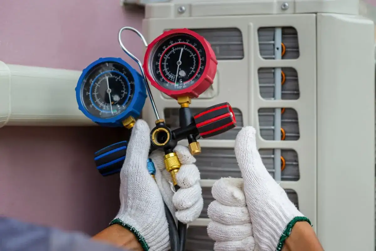 Technicien v&eacute;rifiant la pression d'une pompe &agrave; chaleur avec un manom&egrave;tre. Un geste pour assurer la fiabilit&eacute; de l'appareil.