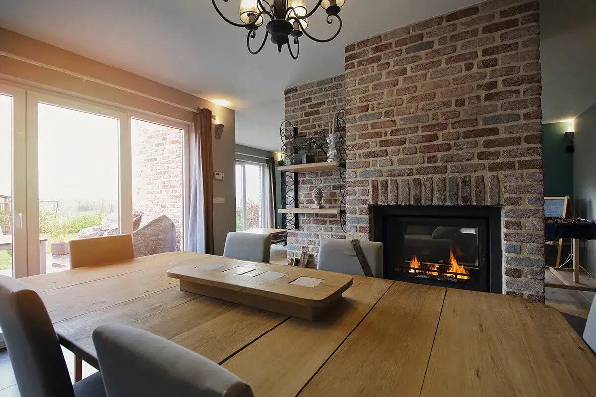 Salle &agrave; manger chaleureuse avec chemin&eacute;e en briques et insert moderne. Id&eacute;al pour un projet ma prime r&eacute;nov insert chemin&eacute;e.