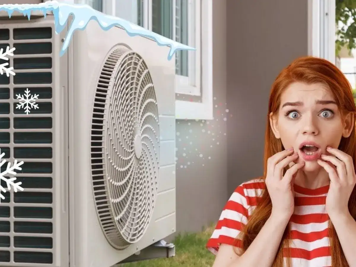 Une unit&eacute; ext&eacute;rieure de climatisation givre, provoquant la surprise d'une jeune femme. Des flocons de neige et de la glace ornent l'appareil.