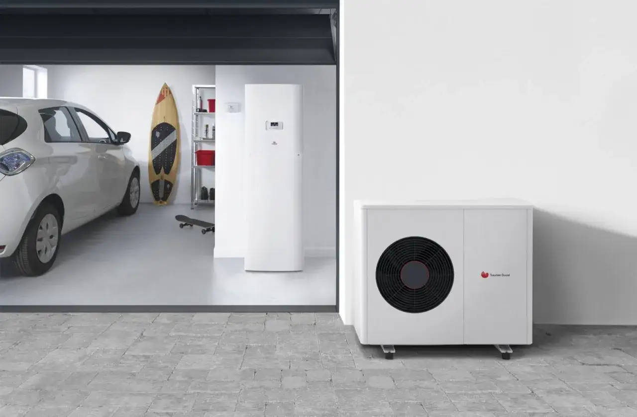 Un probl&egrave;me avec la pompe &agrave; chaleur Saunier Duval ? L'unit&eacute; ext&eacute;rieure est visible &agrave; c&ocirc;t&eacute; d'une voiture &eacute;lectrique dans un garage.