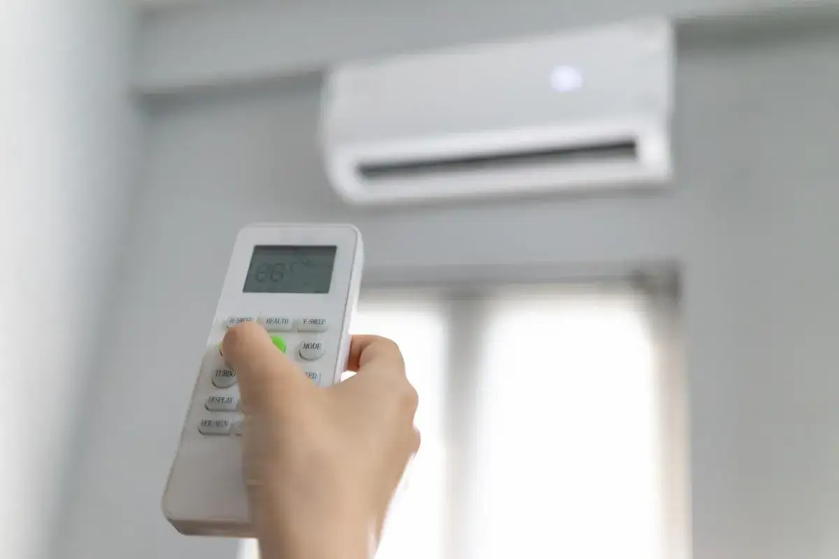 Main tenant utilise la t&eacute;l&eacute;commande pour r&eacute;gler le climatiseur, assurant un confort optimal avec prime cee climatisation.