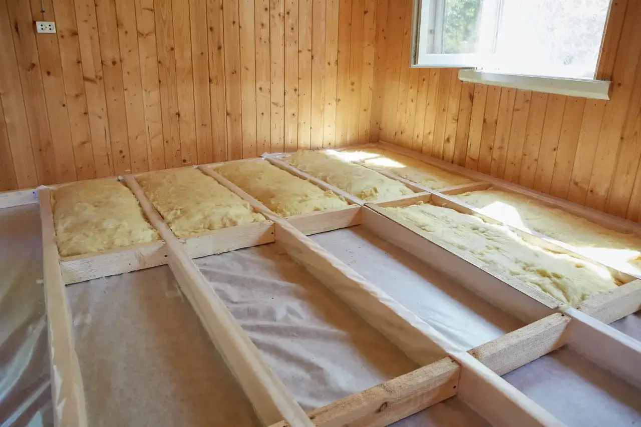 Travaux d'isolation plancher bois en cours, avec laine minérale posée entre les solives.