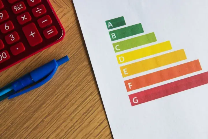 Calculatrice rouge, stylo bleu et graphique DPE. Le gel des loyers pourrait impacter les logements classés E.